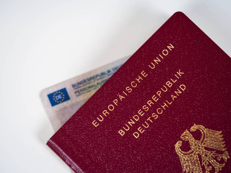 Ein deutscher Reisepass und ein Personalausweis liegen teilweise übereinander auf einem weißen Hintergrund.