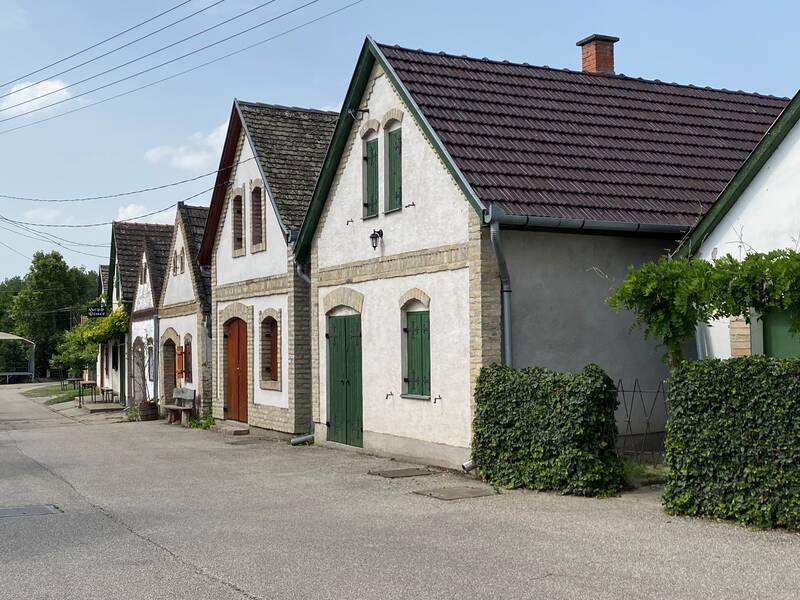 Eine Reihe traditioneller Häuser mit Spitzdächern und grünen Fensterläden steht entlang einer ruhigen Straße.