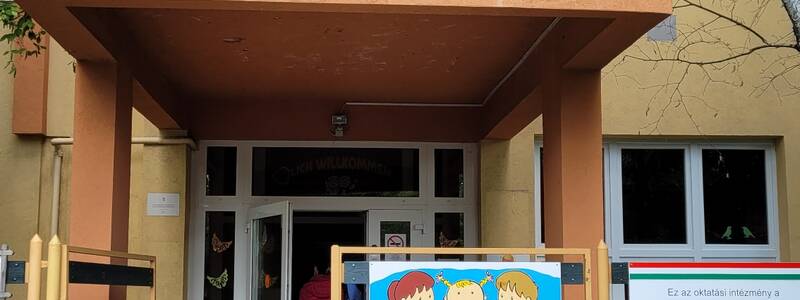 Der Eingang der Sankt Emmerich Grundschule ist mit verschiedenen Hinweisschildern dekoriert und von Flaggen flankiert.