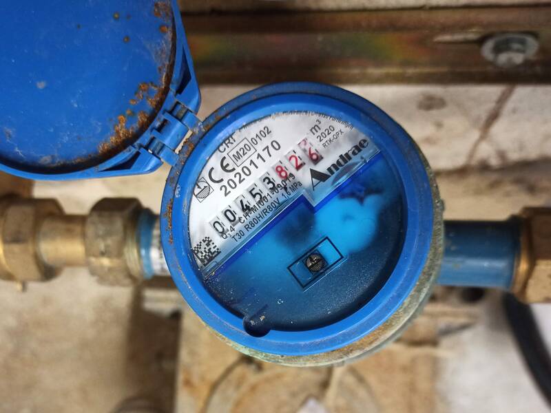 Ein blauer Wasserzähler mit geöffnetem Deckel zeigt einen Messwert von 45,3826 Kubikmetern an.